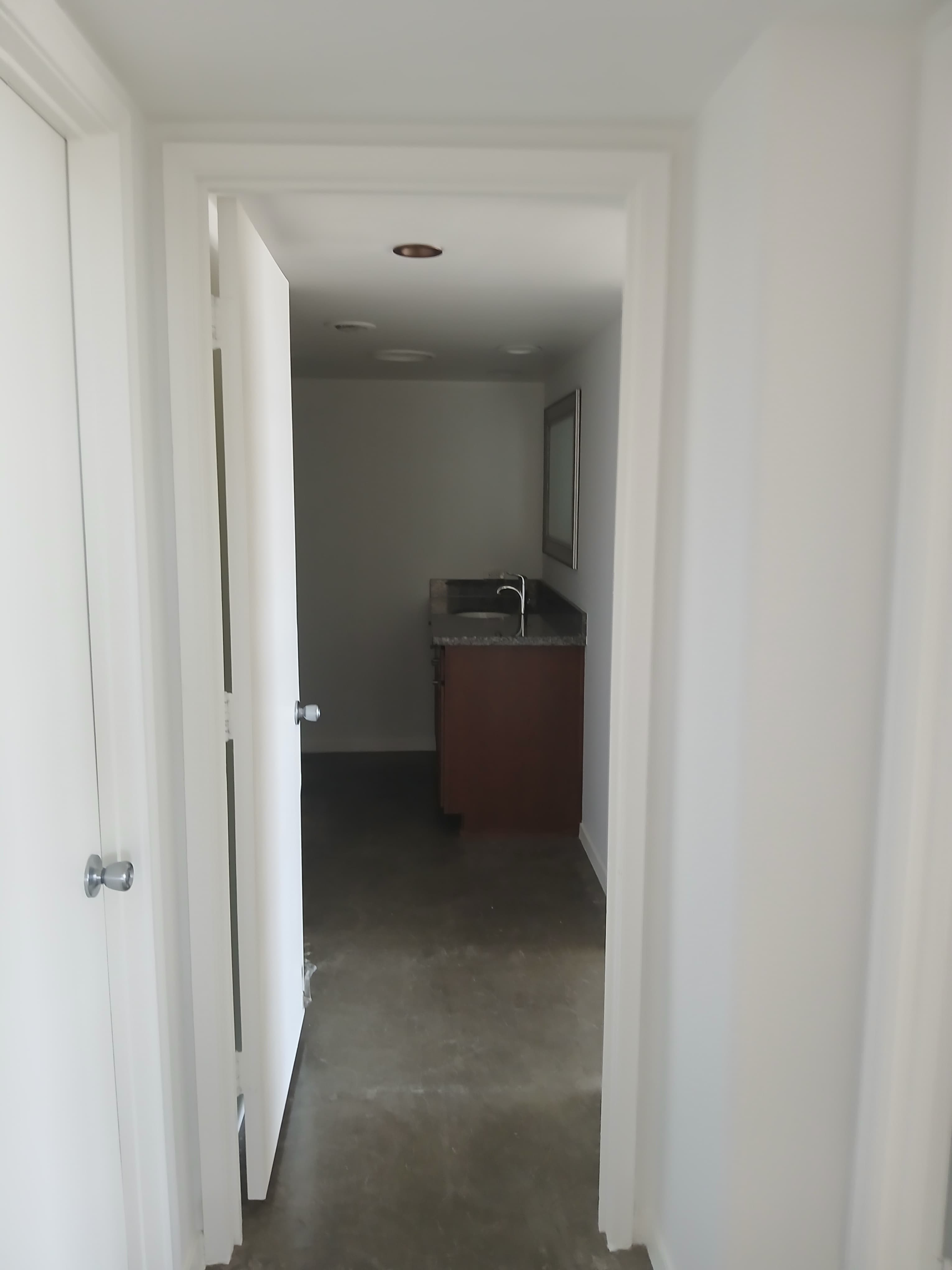 View through a white doorway into a room with a dark wood vanity and sink.